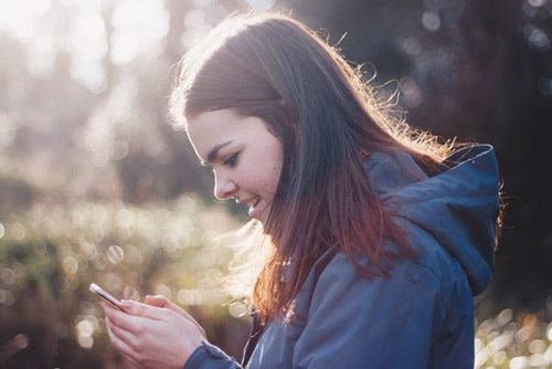 Woman smiling at a smartphone