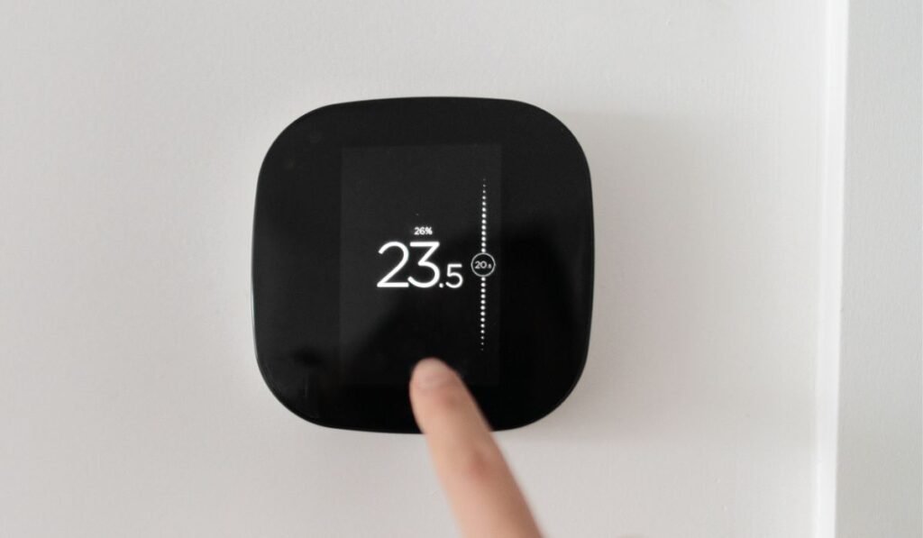 Femme à écran tactile thermostat numérique maison intelligente touchant l'écran tactile pour régler la température de chauffage dans le salon